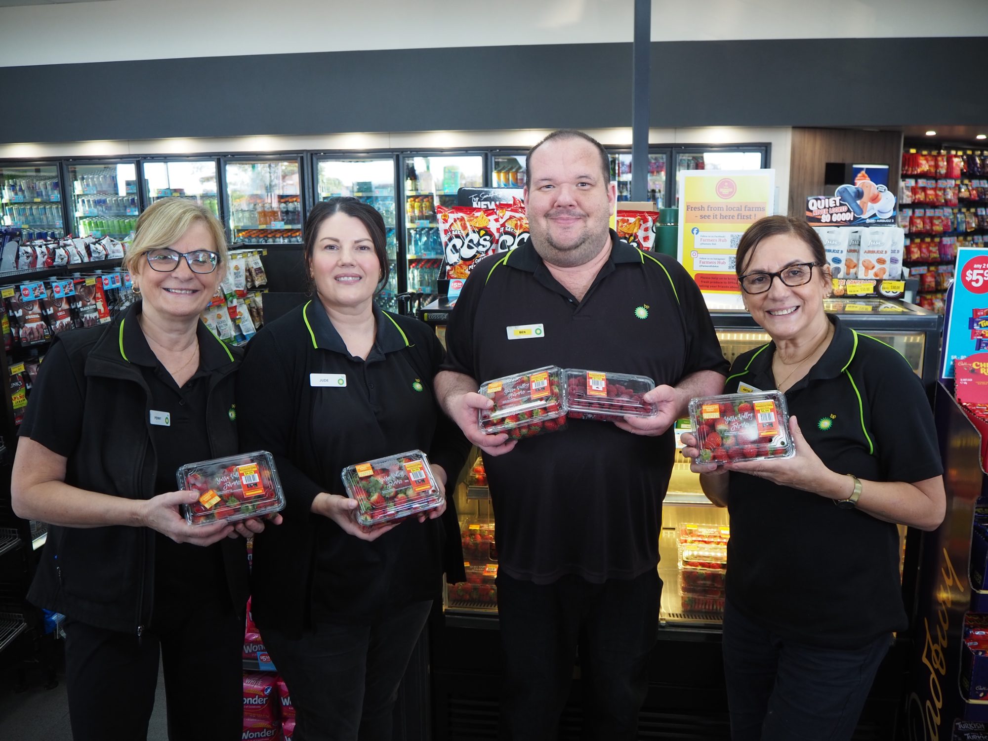 BP store team smiling next to a Farmers Hub display